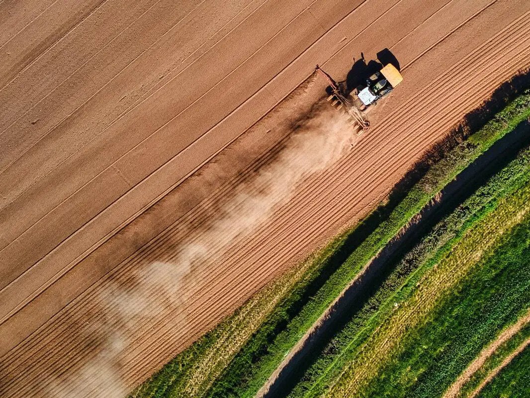 Aerial view of a tractor working between a ploughed and a cropped field, Veneto plain